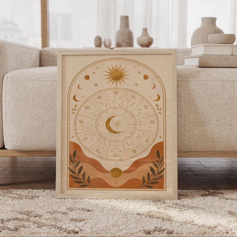 Zodiac wheel wall art print featuring warm ochre gold, terracotta, cream, and deep olive accents, celestial sun and moon motifs, zodiac symbols, and delicate constellation details in a vintage boho style, framed and leaning against a beige sofa on a textured rug in a bright Scandinavian living room.