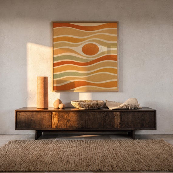 Abstract wavy sun print hanging above a dark wood console and jute rug in a warm neutral interior.