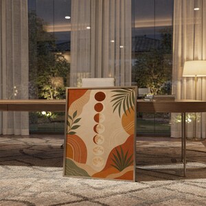 Boho moon phases art print standing on a wooden desk in a home office in warm evening light.