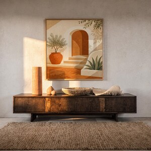 Mediterranean terracotta stairway arch print hanging above a dark wood console and jute rug in a warm neutral interior.