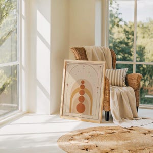 Abstract terracotta geometric print leaning on floor near armchair in sunlit room.