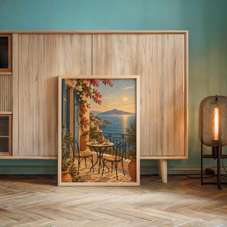 Mediterranean balcony wall art print leaning against a wooden cabinet by a teal wall beside a glowing floor lamp.