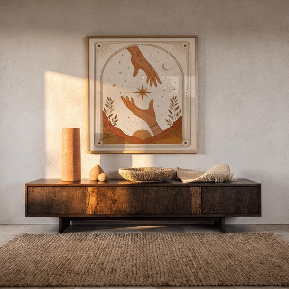 Terracotta spiritual hands tarot art framed on dark wooden console table in warm sunlit room.