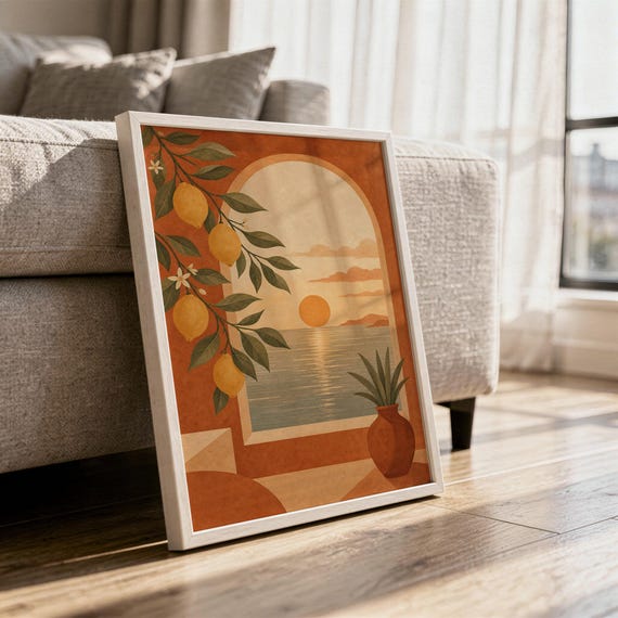 Mediterranean lemon and sea view arch print in a white frame leaning against a gray sofa on a sunlit wooden floor.