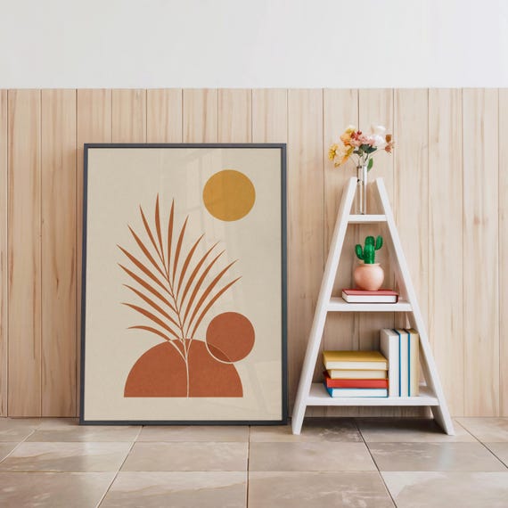 Palm leaf wall art in black frame on floor beside white decorative ladder shelf