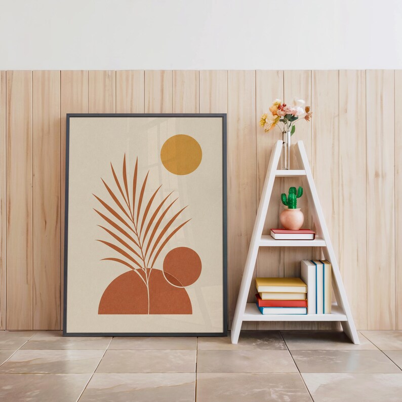 Palm leaf wall art in black frame on floor beside white decorative ladder shelf
