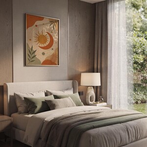 Celestial sun and moon art print hanging above a bed with sage green pillows in a calm neutral bedroom.