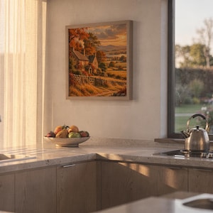 Autumn cottage landscape wall art print hanging above a stone countertop with a fruit bowl in a sunny kitchen.
