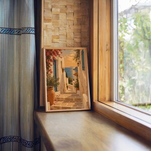 Mediterranean coastal village wall art print standing on a wooden window sill in warm natural light.