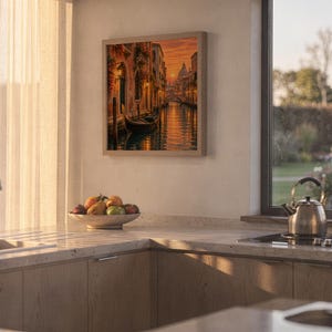 Venice canal sunset wall art print hanging above a stone countertop with a fruit bowl in a sunny kitchen.