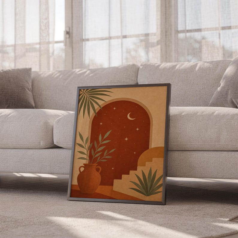Terracotta moon and stars arch art print leaning against a white sofa in a bright living room with sheer curtains.