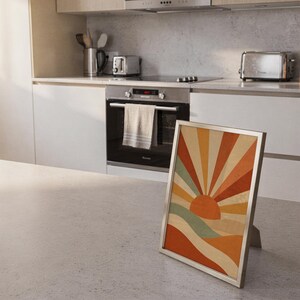 Retro geometric sunrise print standing on a countertop in a modern white kitchen.