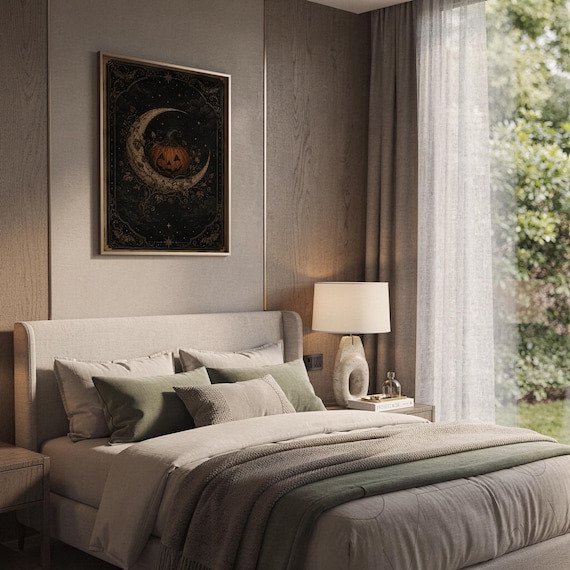 Vintage halloween moon wall art print hanging above a bed with sage green pillows in a calm neutral bedroom.