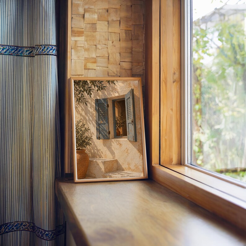 Mediterranean blue shutter wall art print standing on a wooden window sill in warm natural light.