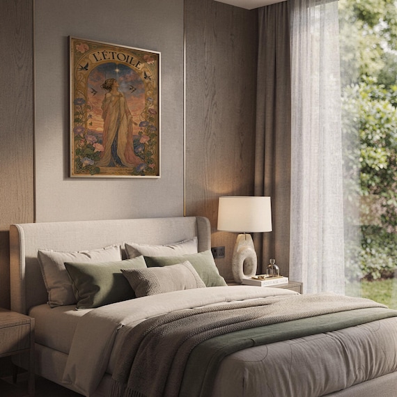 The L Etoile poster hanging on a paneled bedroom wall above a bed dressed with neutral pillows and a green throw blanket.