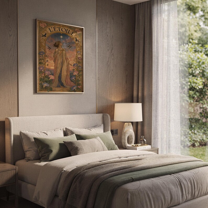 The L Etoile poster hanging on a paneled bedroom wall above a bed dressed with neutral pillows and a green throw blanket.