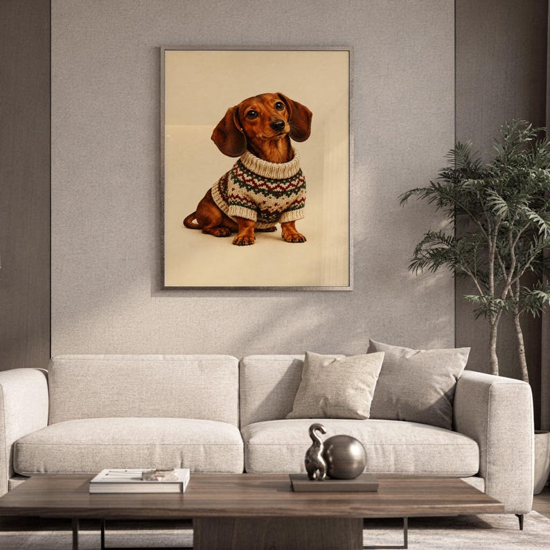 Dachshund sweater wall art print leaning against a white sofa in a bright living room with sheer curtains.