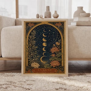 Moon phase wall art print featuring deep navy blue, antique gold, olive green, warm rust, and cream tones, glowing lunar phases, constellations, lotus flowers, and Art Nouveau botanical details, framed and leaning against a beige sofa on a textured rug in a bright Scandinavian living room.