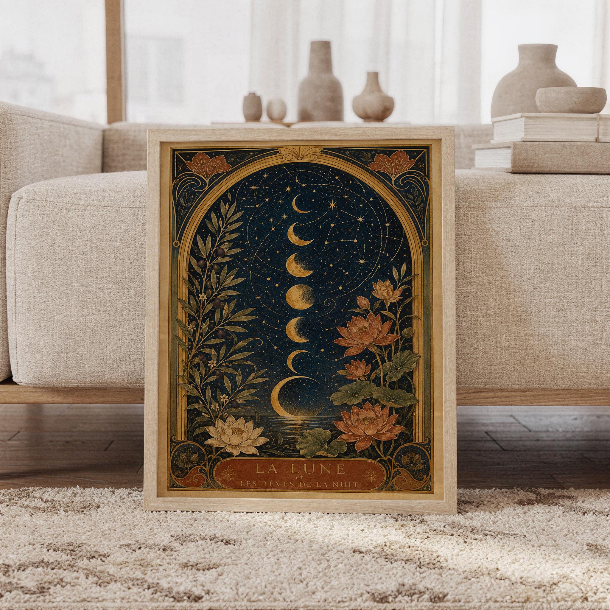 Moon phase wall art print featuring deep navy blue, antique gold, olive green, warm rust, and cream tones, glowing lunar phases, constellations, lotus flowers, and Art Nouveau botanical details, framed and leaning against a beige sofa on a textured rug in a bright Scandinavian living room.