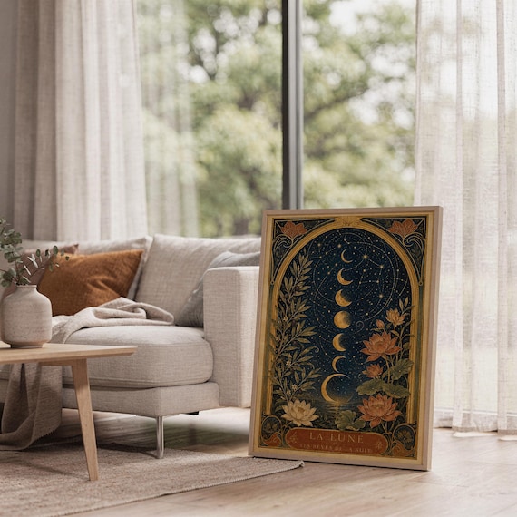 Moon phase wall art print leaning on the floor beside a cream armchair next to large garden windows.