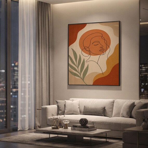 Abstract line art face print showing a continuous line drawing of a woman's face with organic shapes and leaves in terracotta, ochre, cream and sage, hanging above a light gray sofa in a modern living room with evening city views through tall windows.