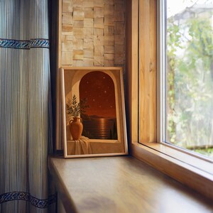 Mediterranean night sea wall art print standing on a wooden window sill in warm natural light.