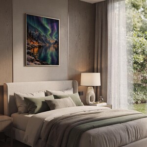 Aurora borealis mountain landscape wall art print hanging above a bed with sage green pillows in a calm neutral bedroom.