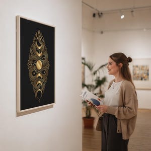 Gold snake moon phase wall art print in a silver frame leaning against a sofa beside a decorative marble sphere.