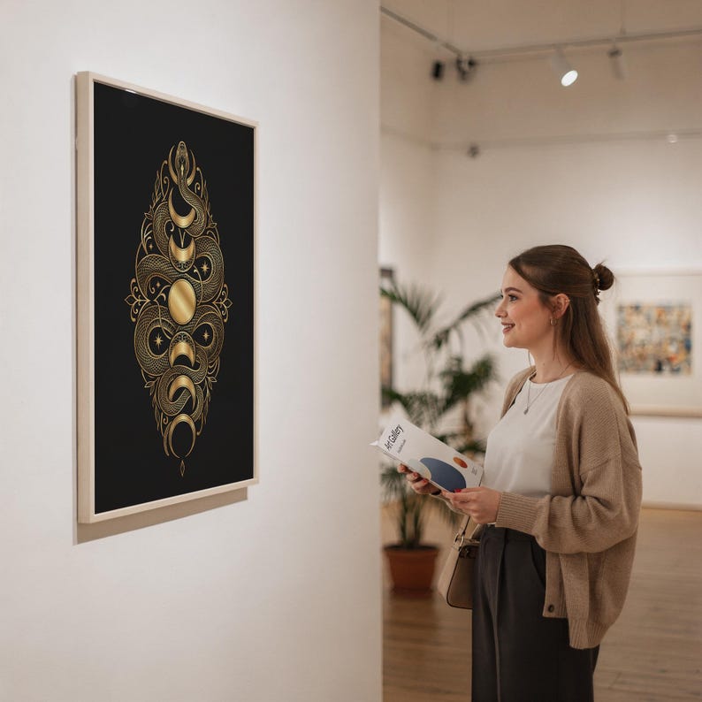 Gold snake moon phase wall art print in a silver frame leaning against a sofa beside a decorative marble sphere.