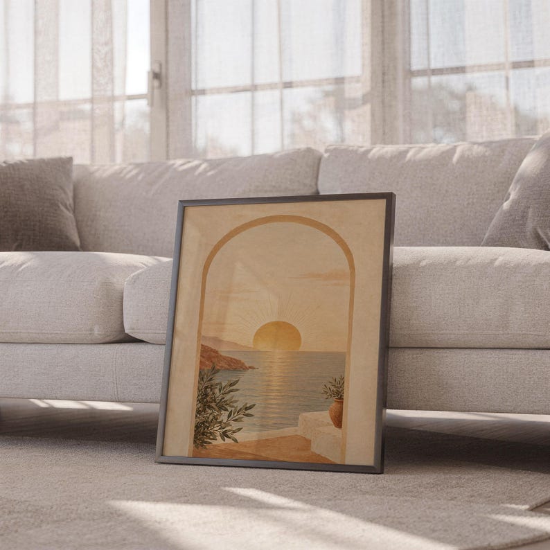 Mediterranean sunset arch print leaning against a white sofa in a bright living room with sheer curtains.