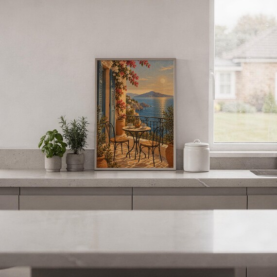 Mediterranean balcony wall art print standing on a white kitchen counter beside potted herbs.