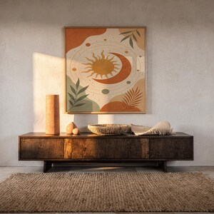 Celestial sun and moon art print hanging above a dark wood console and jute rug in a warm neutral interior.