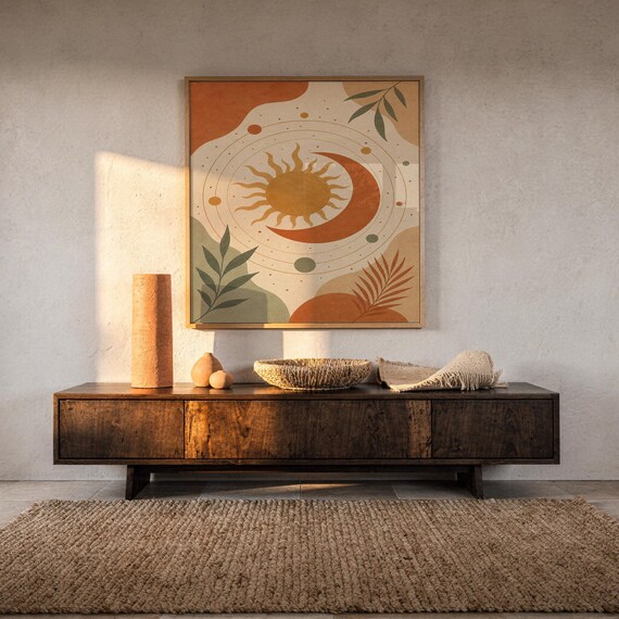 Celestial sun and moon art print hanging above a dark wood console and jute rug in a warm neutral interior.