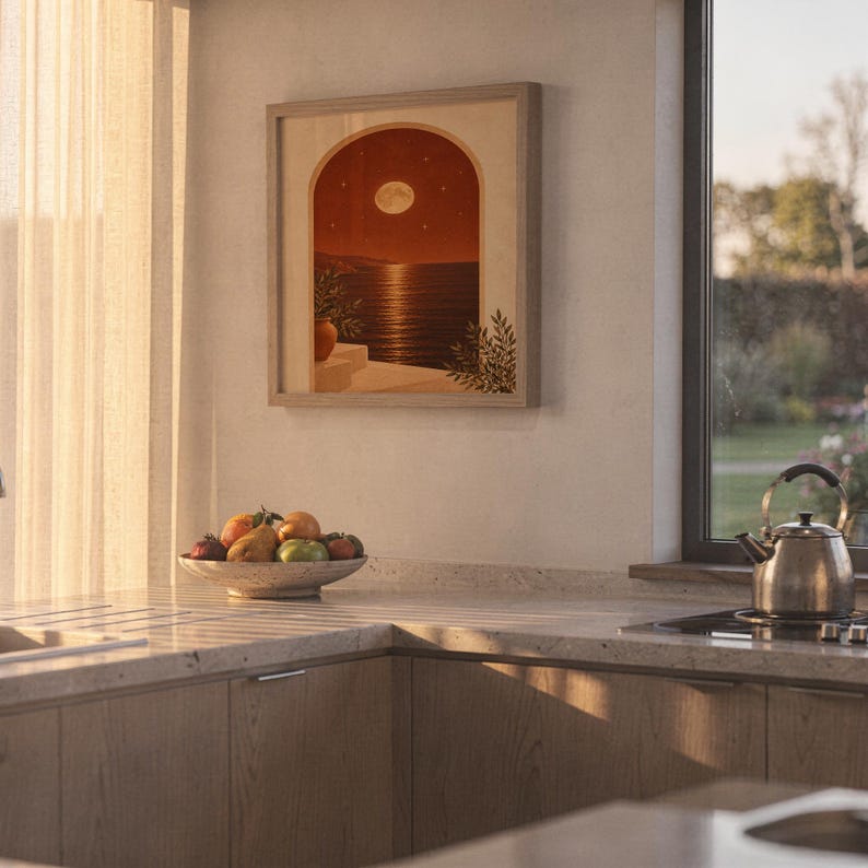 Moonlit Mediterranean arch print hanging above a stone countertop with a fruit bowl in a sunny kitchen.
