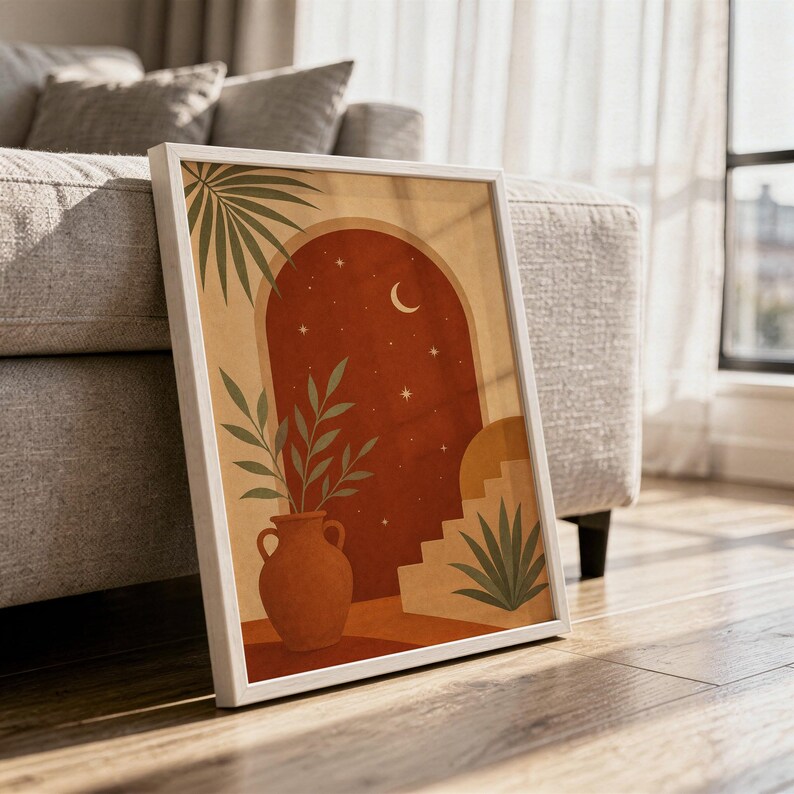 Terracotta moon and stars arch art print in a white frame leaning against a gray sofa on a sunlit wooden floor.