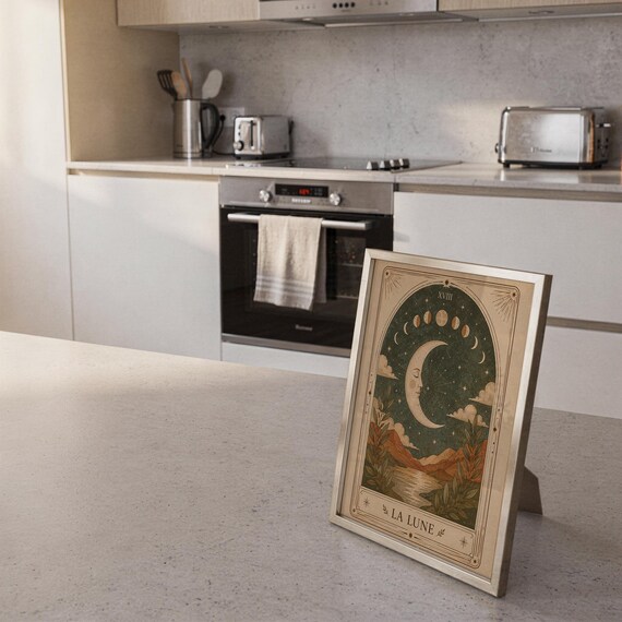 Vintage crescent moon tarot print framed on kitchen island counter in modern bright home.