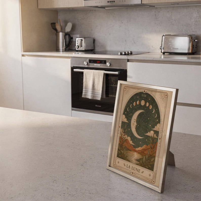 Vintage crescent moon tarot print framed on kitchen island counter in modern bright home.
