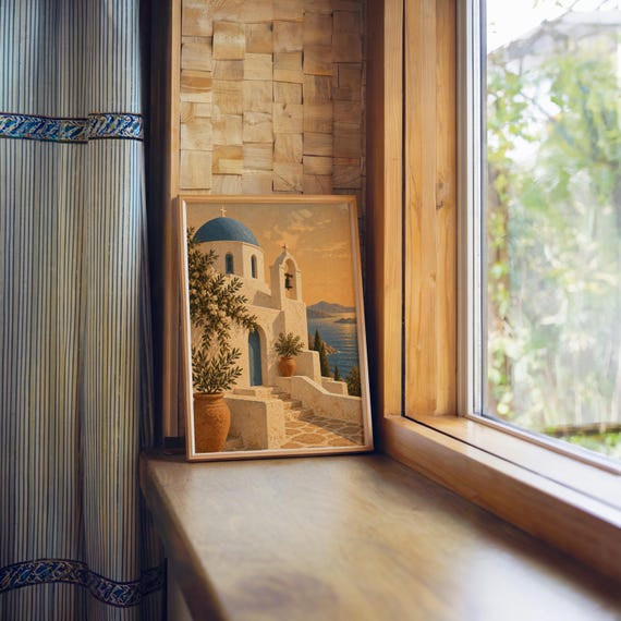 Santorini church wall art print standing on a wooden window sill in warm natural light.