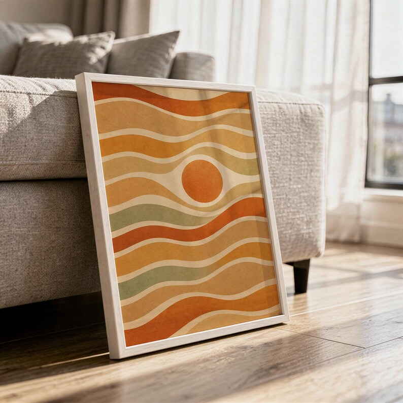 Abstract wavy sun print in a white frame leaning against a gray sofa on a sunlit wooden floor.