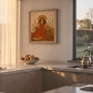 Celestial goddess wall art print hanging above a stone countertop with a fruit bowl in a sunny kitchen.