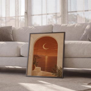 Mediterranean crescent moon arch print leaning against a white sofa in a bright living room with sheer curtains.