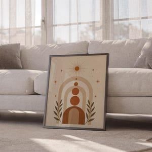 Boho arch and celestial star poster framed leaning against sofa in cozy sunlit living room setup.