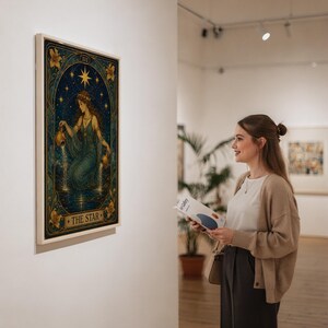 The star tarot card wall art print in a silver frame leaning against a sofa beside a decorative marble sphere.