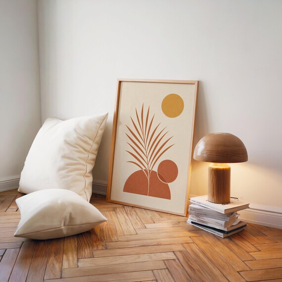 Terracotta palm leaf poster leaning on floor next to wooden lamp and cushions