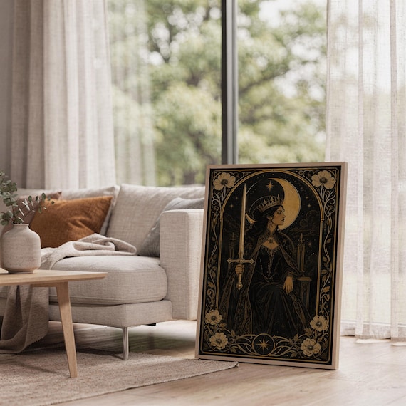 Gothic moon queen wall art print leaning on the floor beside a cream armchair next to large garden windows.