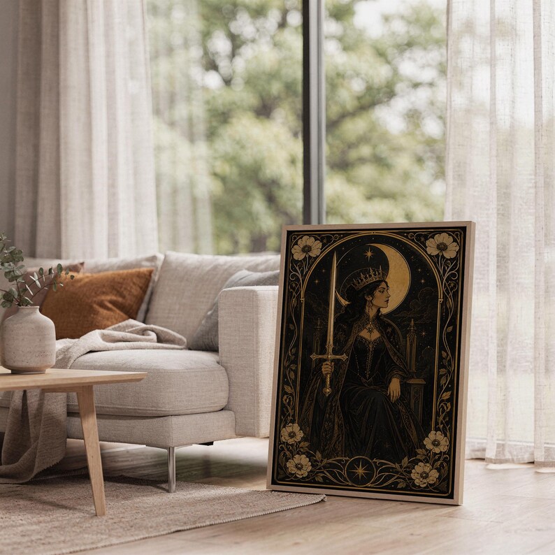 Gothic moon queen wall art print leaning on the floor beside a cream armchair next to large garden windows.