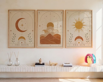 May include: Three framed wall art prints featuring tarot-inspired designs in muted earth tones. The left print shows a crescent moon, the center shows a sun over mountains, and the right shows a sun. Each print includes arches and stars.