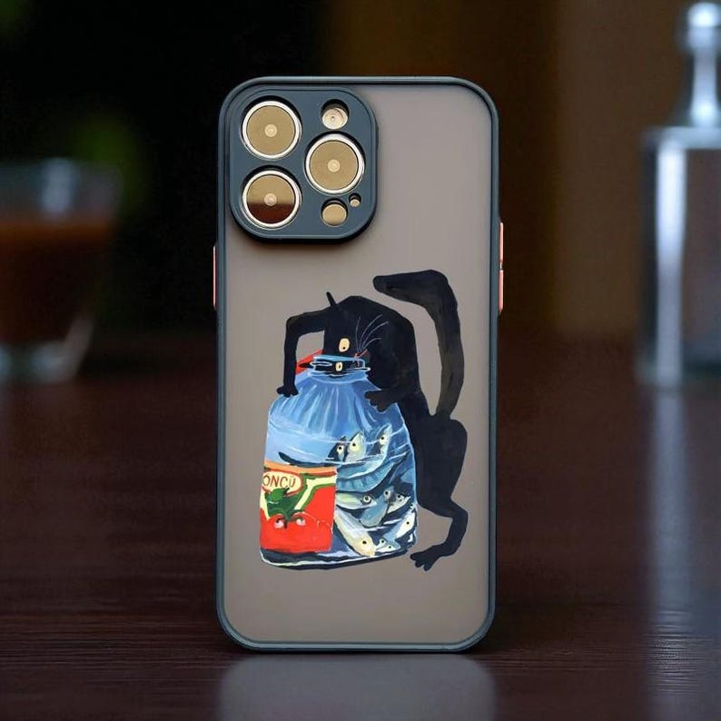 以下が含まれることがあります： 黒猫のイラストが描かれたスマホケース。猫は魚の入った青い瓶に手を伸ばしています。ケースは濃いグレーの背景と黒い縁取りです。カメラレンズは金色です。
