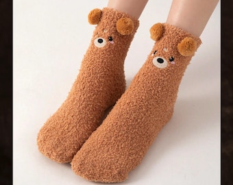 May include: A pair of brown fluffy socks featuring embroidered bear faces. The socks have small, round ears at the top. The text "Nova Clean Store" is visible in the top left corner.