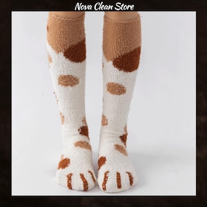 Könnte beinhalten: Kniestrümpfe mit einem Katzenpfoten-Design. Die Socken sind weiß mit braunen und beigen Flecken und Pfotenabdrücken auf den Zehen. Sie bestehen aus einem weichen, flauschigen Material. Der Text "Nova Clean Store" befindet sich oben.